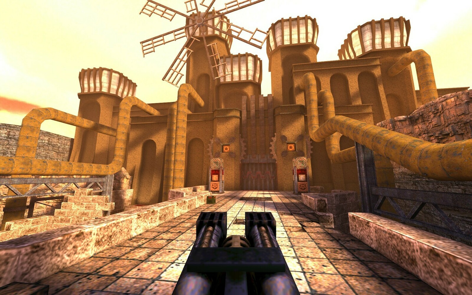 Vue à la première personne dans Quake, face à une forteresse ocre surmontée d’un moulin à vent, arme à double canon au premier plan