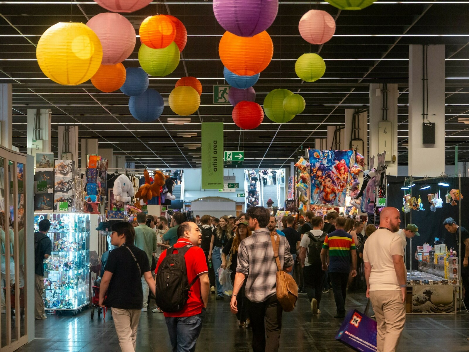 Une allée de la gamescom 2026 sous des lanternes en papier, avec une foule de visiteurs entre les stands