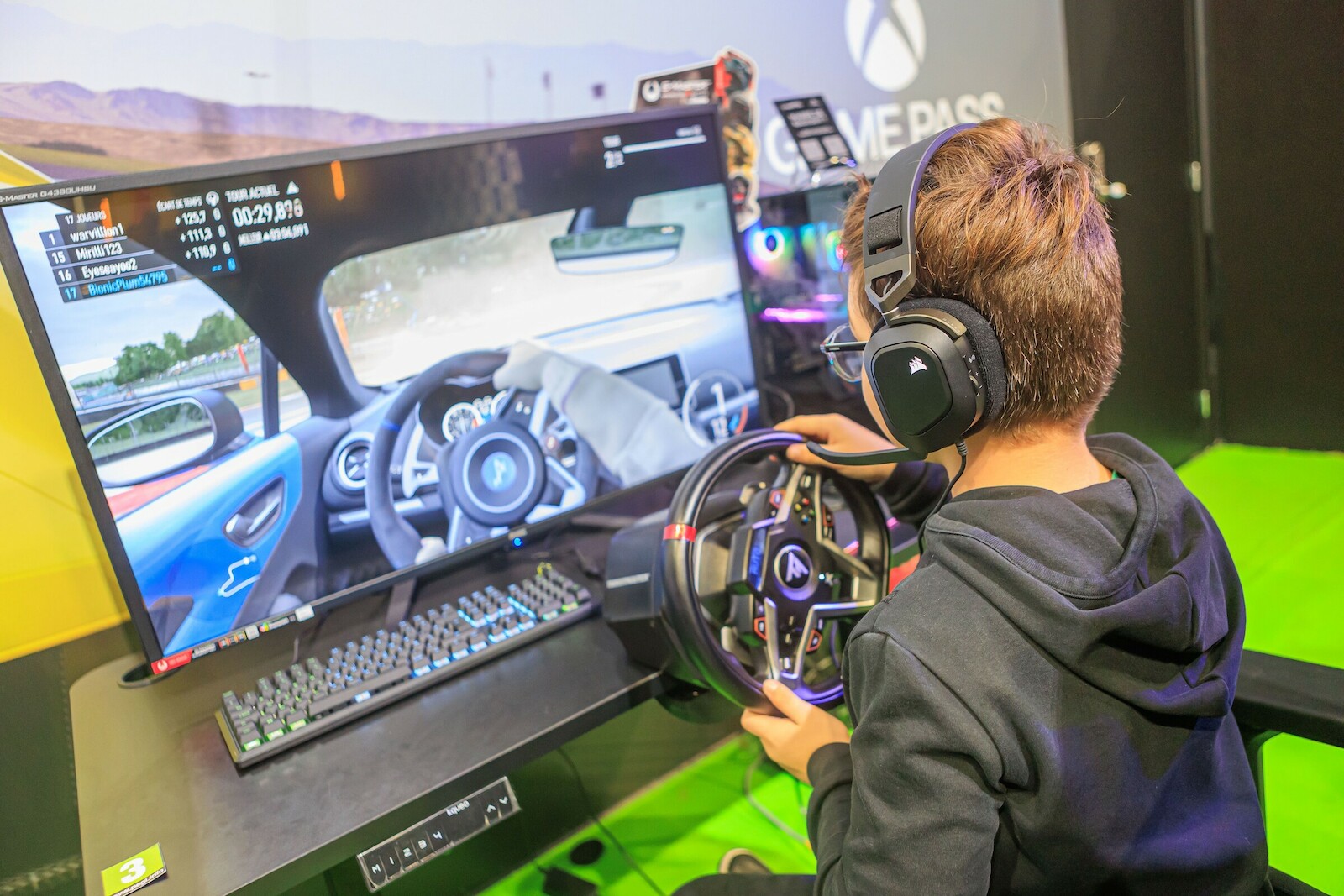Un jeune visiteur joue à un jeu de course au volant sur un stand du salon